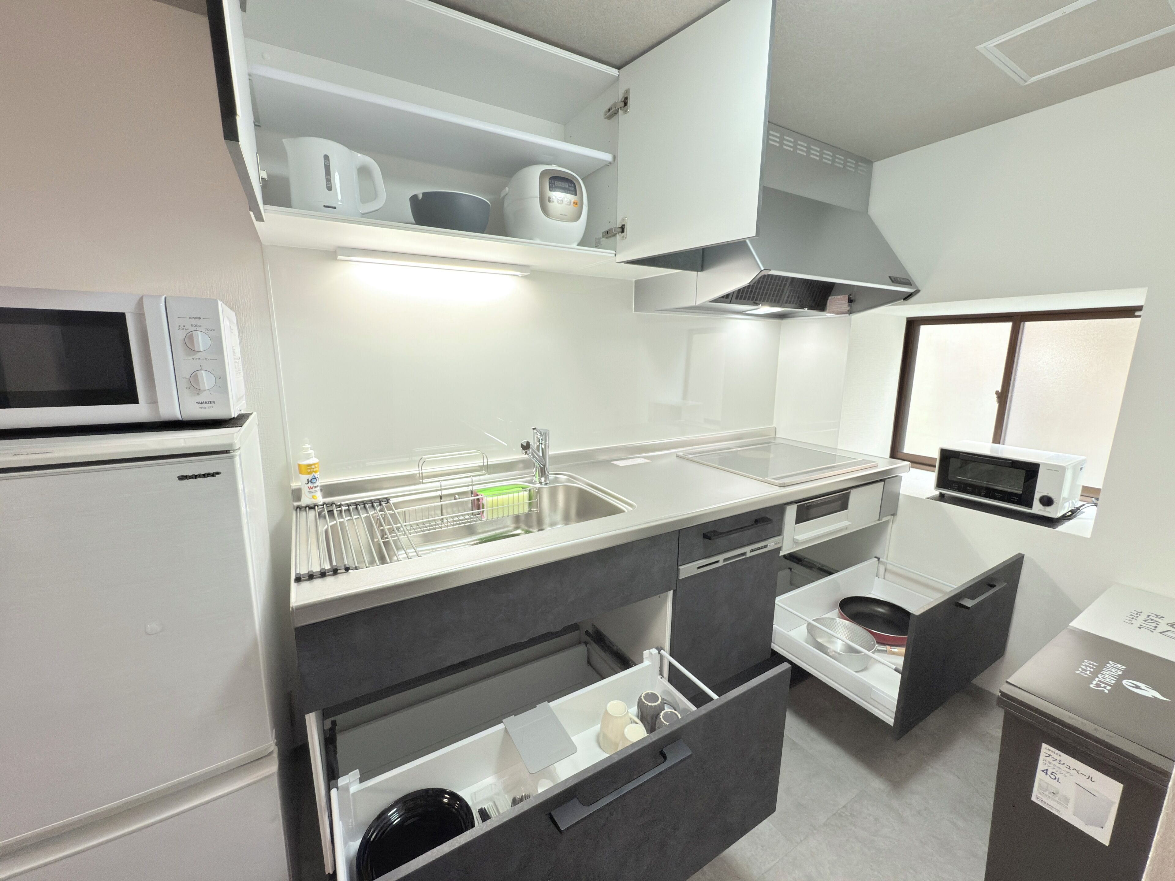 Una cocina compacta con microondas, pileta y horno empotrado.