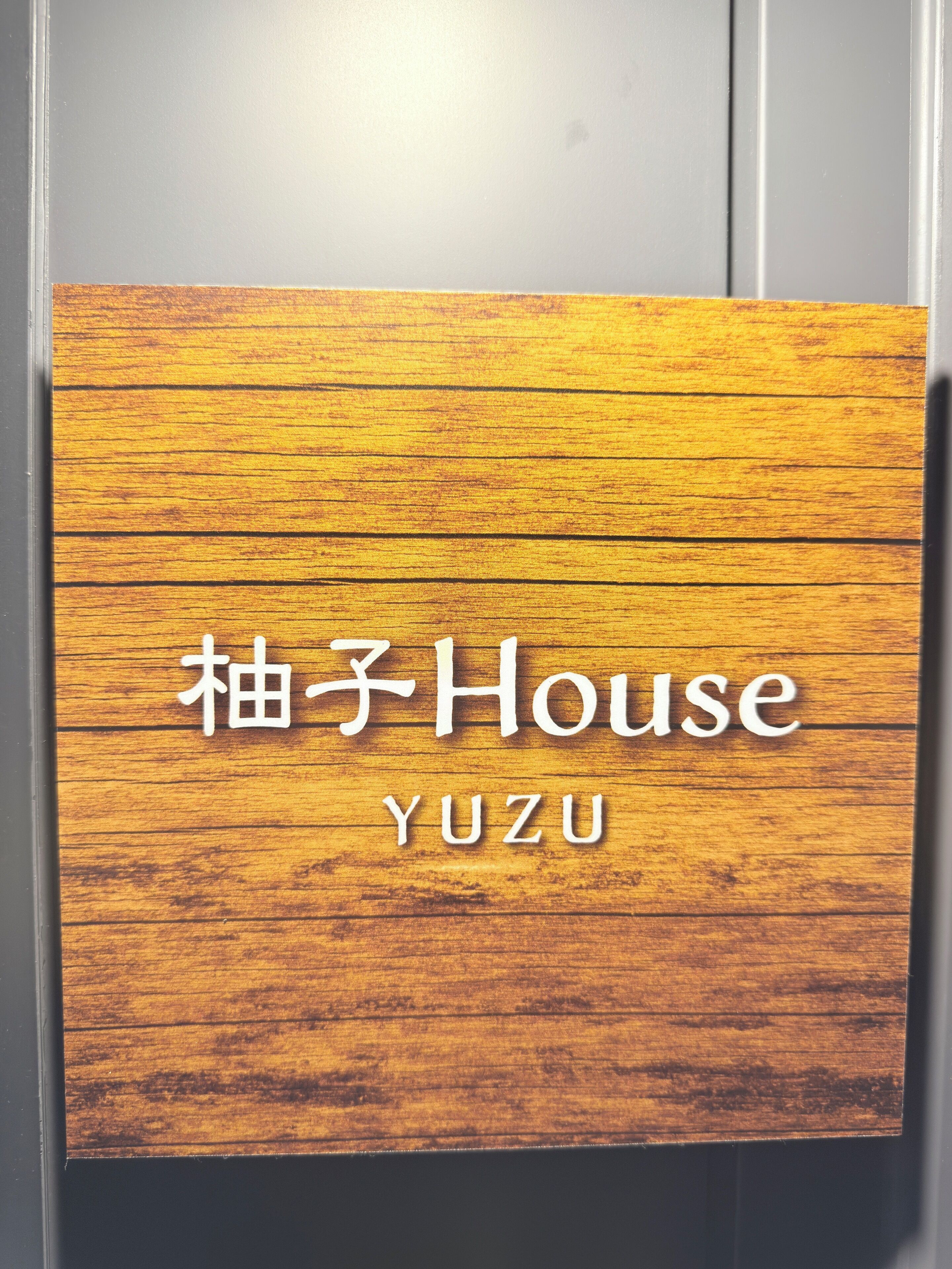 Et træskilt med teksten "Yuzu House" og "YUZU".