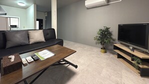 Un salon moderne avec un canapé, une table basse, un téléviseur et une plante en pot.