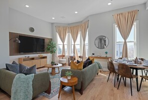 A modern living room with a sofa, a dining table, and a TV.