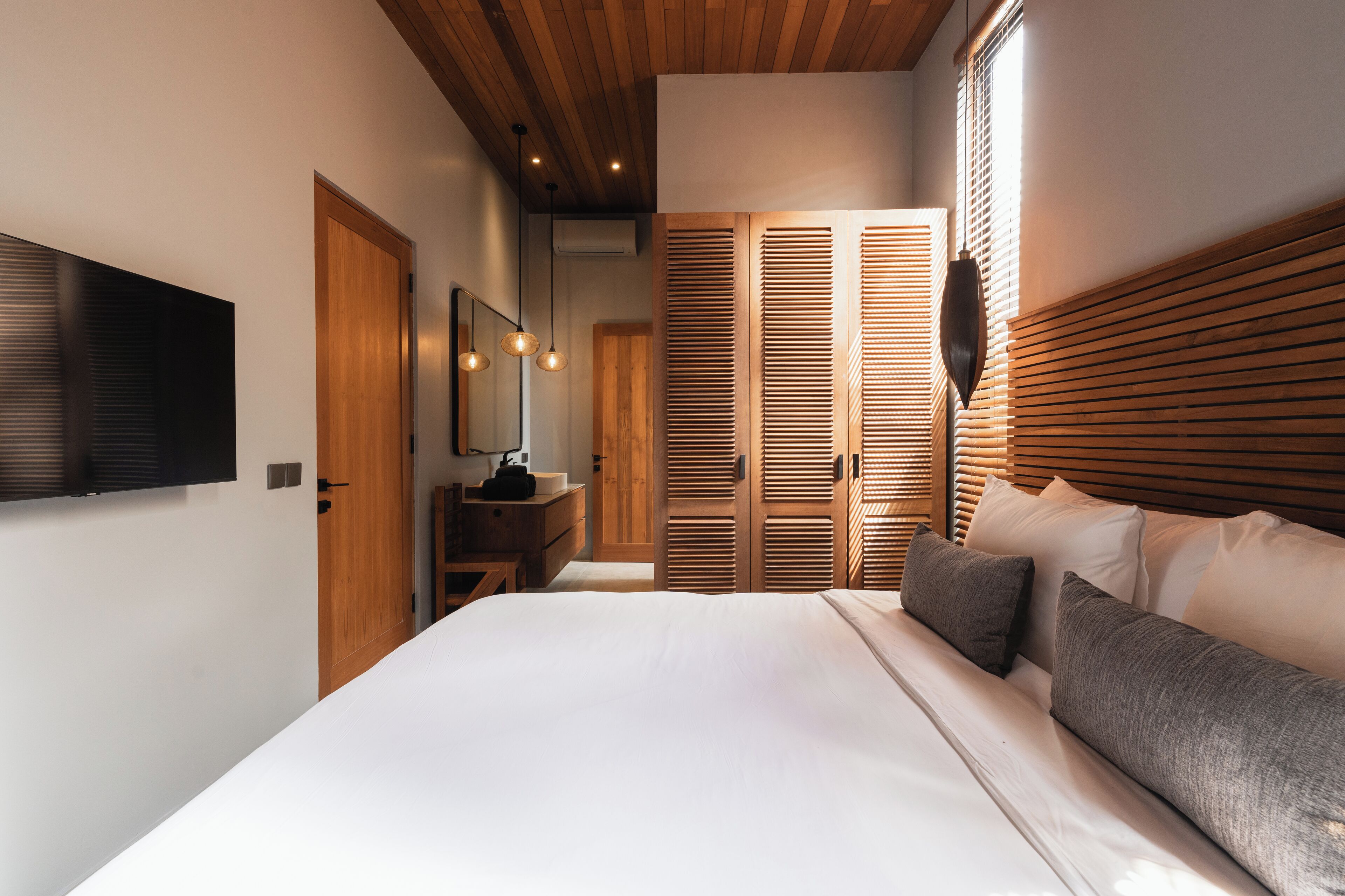 Un dormitorio con una cama grande, cabecero de madera y un televisor en la pared.