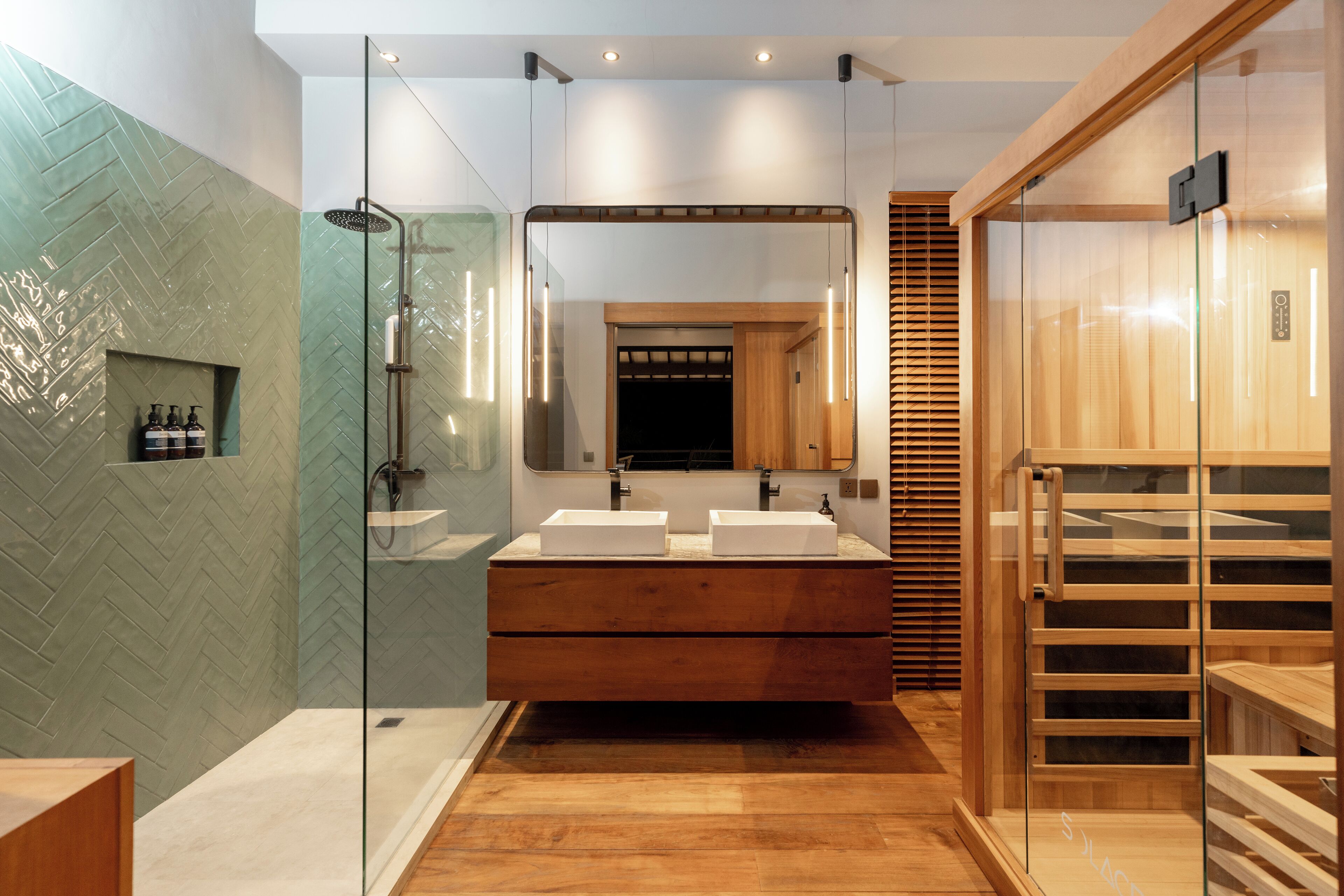 Une salle de bain moderne avec une douche à l’italienne en verre, deux vasques et un meuble-lavabo en bois.