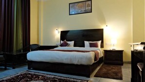 Ein Hotelzimmer mit einem großen Bett, zwei Nachttischen, einem Sessel, einem Schreibtisch und einem Teppich.