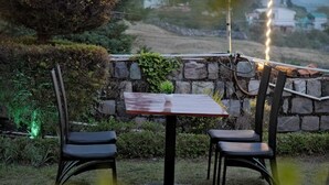 Ein Außenbereich mit Sitzgelegenheiten, einer Steinsäule, zwei Stühlen und einem Tisch.