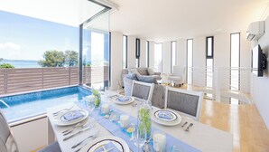 A dining area with a view of the sea, a pool, and a modern interior design. - VILLA BLANC F (Motobu)