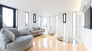 A modern living room with a grey sofa, a white armchair, and a glass coffee table. - VILLA BLANC F (Motobu)