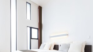 A modern bedroom with a large bed, wooden flooring, and a large window. - VILLA BLANC F (Motobu)