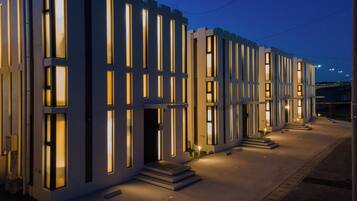 A modern building with a symmetrical facade, featuring evenly spaced vertical windows and a central entrance with steps leading up to it.
