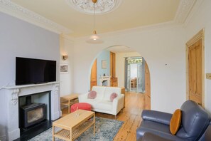 Ein Wohnzimmer mit Kamin, Fernseher, Sofa und Couchtisch.