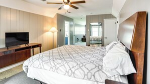 A bedroom with a bed, a TV on a wooden stand, a ceiling fan, and a bathroom visible through an open door. - 12 Mi to BlueOval City: Tennessee Getaway! (Mason)
