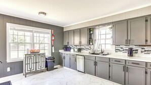 A modern kitchen with grey cabinets, white marble flooring, and a large window. - 12 Mi to BlueOval City: Tennessee Getaway! (Mason)