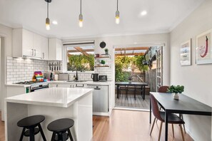 A modern kitchen with white cabinets, a central island, and a dining area with a wooden table and chairs.