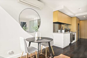 A modern kitchen with a central island, a dining area with a round table and chairs, and a large mirror on the wall.