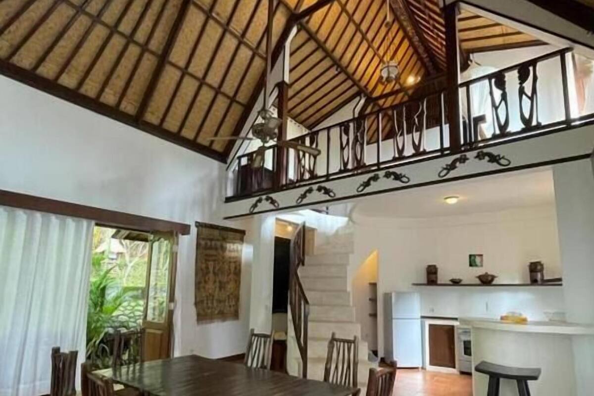 A spacious dining area with a high ceiling and a balcony.
