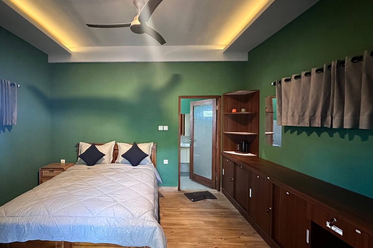 A bedroom with a bed, nightstands, a wardrobe, a ceiling fan, and a window with curtains.