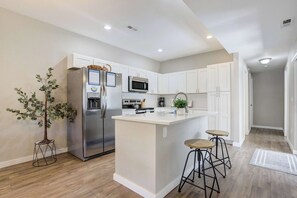 A modern kitchen with white cabinets, stainless steel appliances, and a central island with stools.