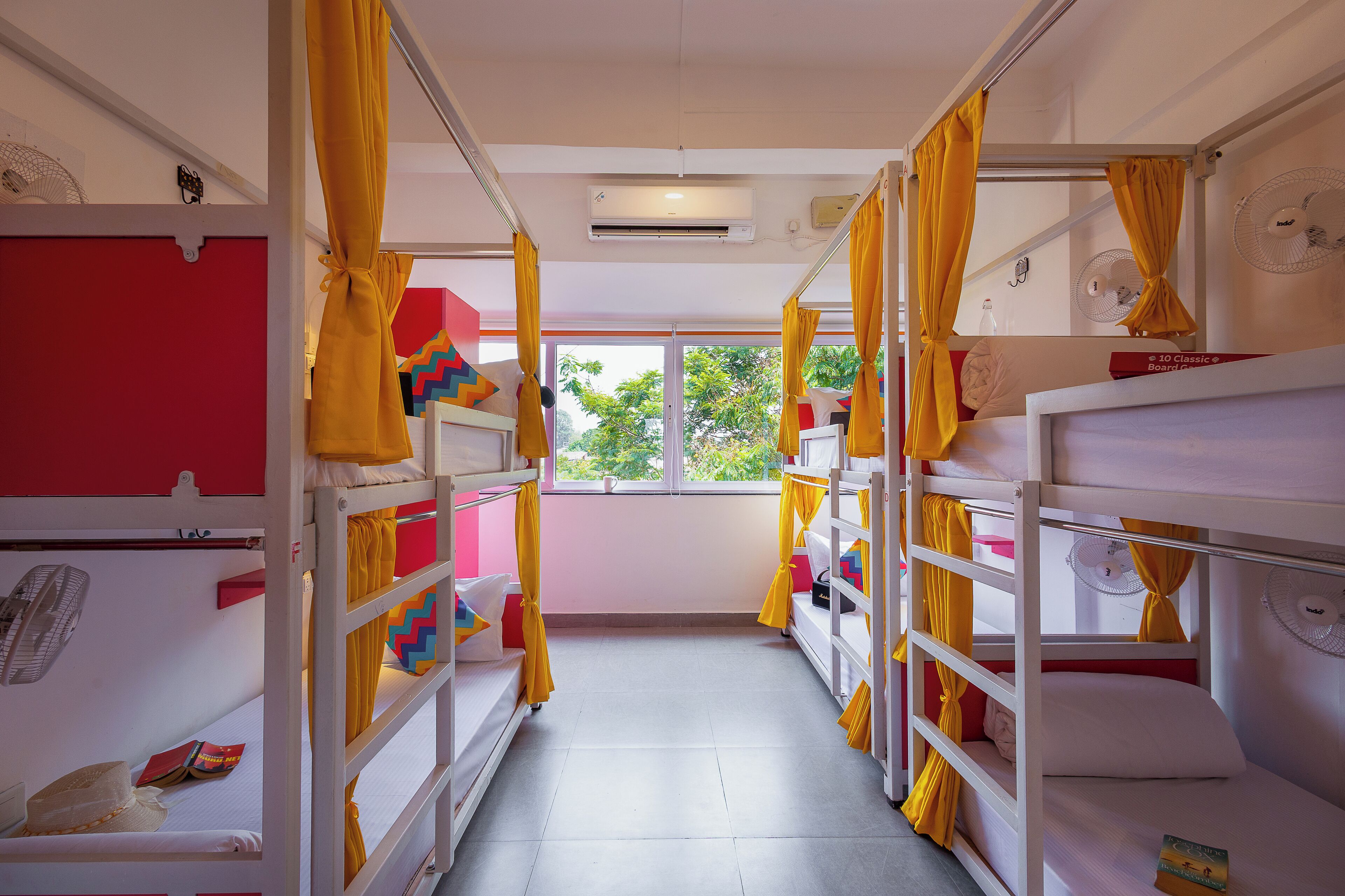 Una camera del dormitorio con letti a castello, tende gialle e ventilatori alle pareti.