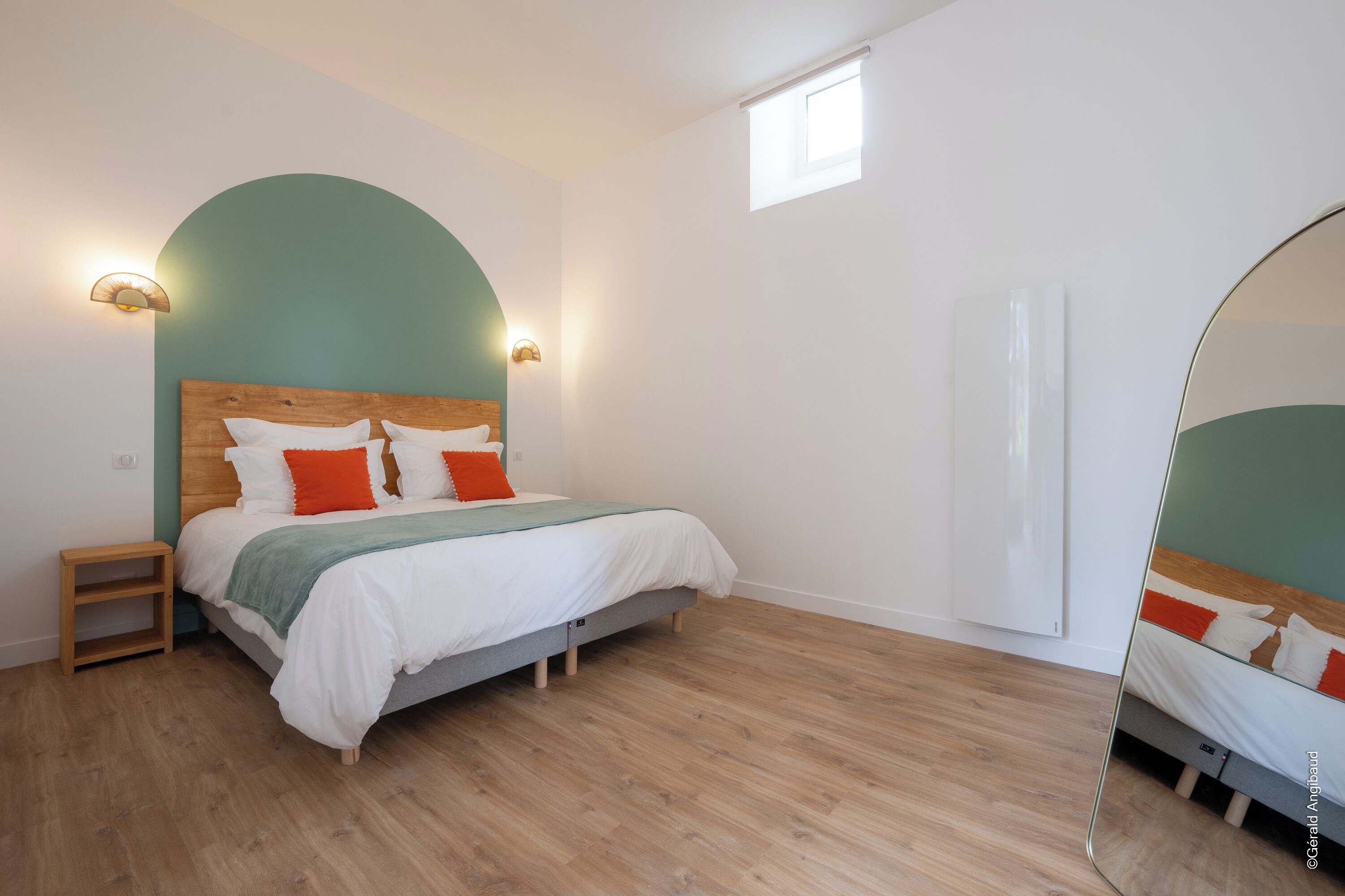 Un dormitorio con cama, mesitas de noche, espejo y ventana.