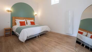Un dormitorio con cama, mesitas de noche, espejo y ventana.