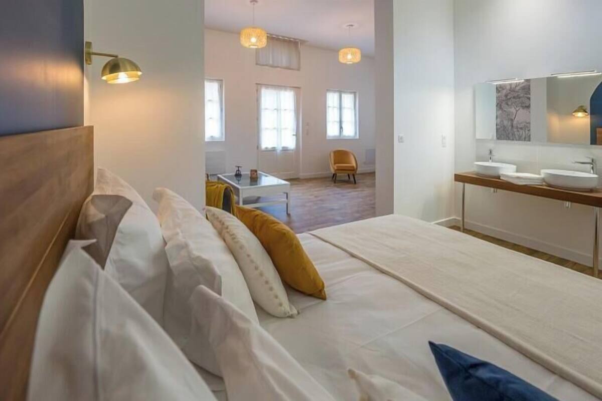 Een hotelkamer met een bed, nachtkastje en een badkamer met spiegel en wastafel.