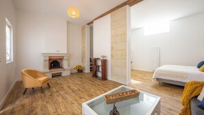 Een kamer met een open haard, een bed, een stoel en een tafel met een mandje.