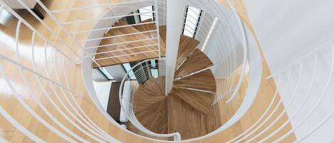 Eine Wendeltreppe mit weißen Geländern und Holzstufen, die zu einer oberen Etage führt.