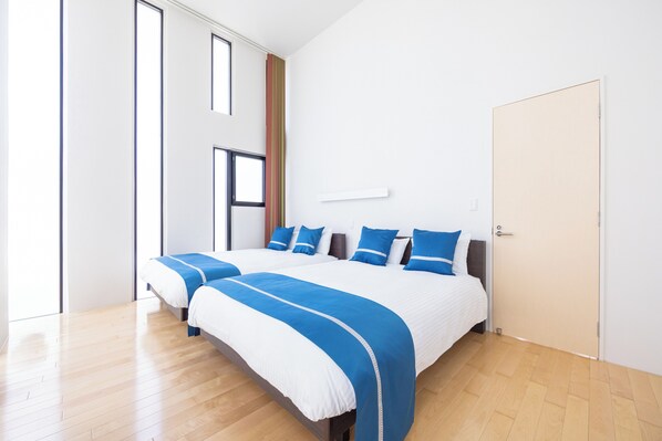 A modern hotel room with a large bed, a window, and a door.
