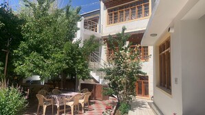 Un patio con zona de comedor, mobiliario exterior y una escalera que lleva a un nivel superior.