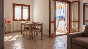 A dining area with a table, chairs, and a view through an open door.