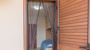 A room with a bed, a wooden door, and a curtain.