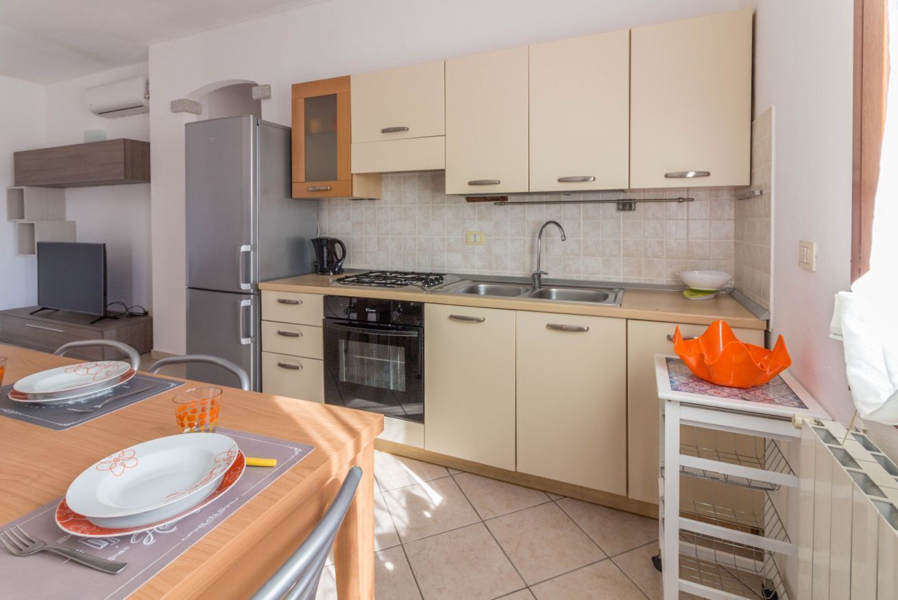 A kitchen with a refrigerator, stove, sink, and cabinets.