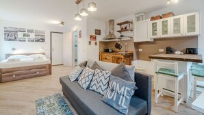 Ein modernes Apartment mit Bett, Schlafsofa, Küchenzeile und Essbereich.