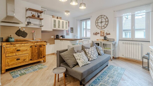 Eine gemütliche Küche mit Holzausstattung, einem grauen Sofa und einer Wanduhr zum Thema Kaffee.