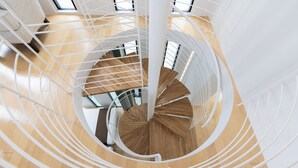 A spiral staircase with white railings and wooden steps, leading to an upper floor. - Villa Blanc H (Motobu)