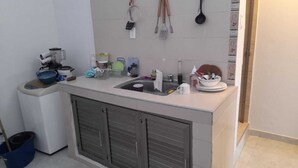 Eine kleine Küche mit Spüle, einem Kühlschrank und verschiedenen Küchenutensilien und Geräten auf der Arbeitsfläche.