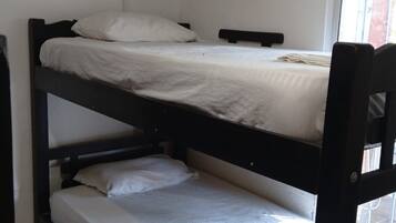 Dormitorio con literas, ventana, aire acondicionado y enchufe en la pared.