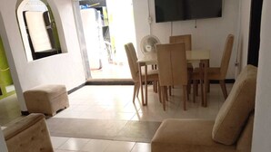 Ein Wohnzimmer mit einer Couch, Hocker und einem Esstisch mit Stühlen.
