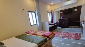 Een hotelkamer met twee eenpersoonsbedden, een bureau, een stoel, een kledingkast en een plafondventilator.