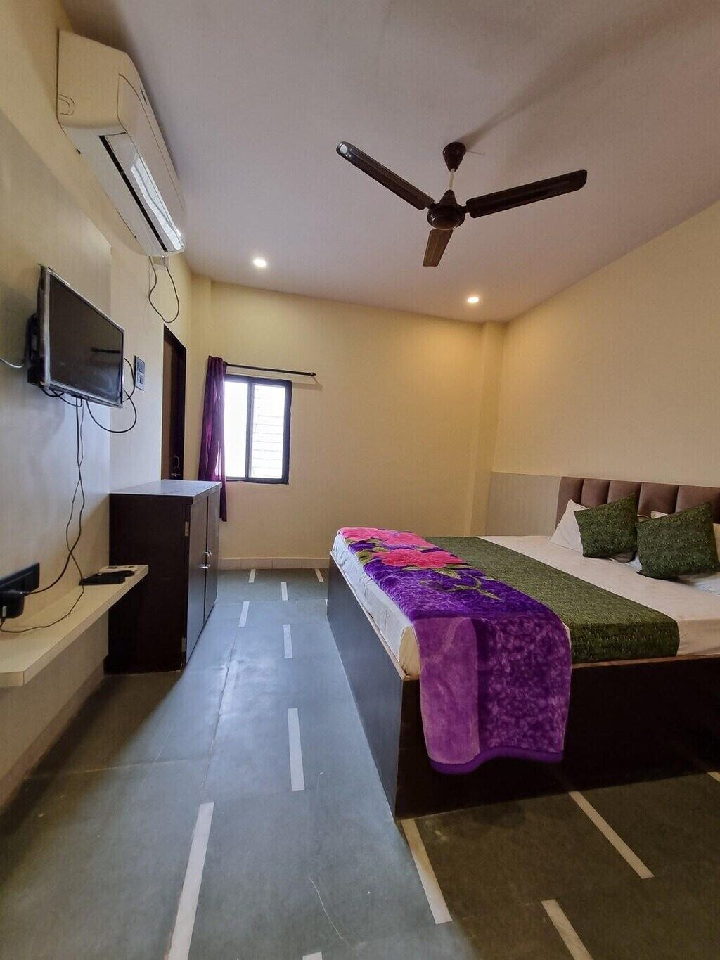 Une chambre d’hôtel équipée d’un lit, d’un bureau, d’une télévision et d’un ventilateur de plafond.
