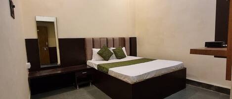 A bedroom with a bed, a nightstand, a mirror, a ceiling fan, and a TV.