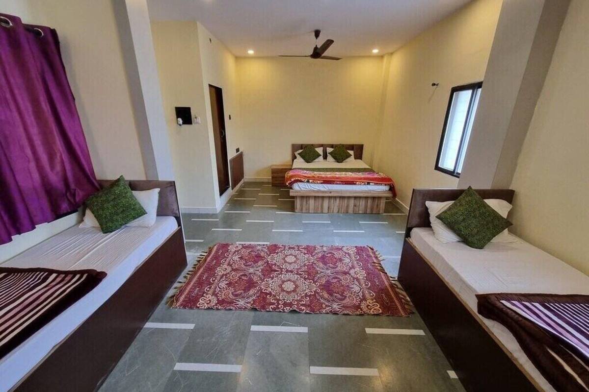 Une chambre d’hôtel avec un lit, deux canapés, un tapis à motifs et un ventilateur de plafond.