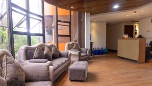 A modern hotel lobby with a reception desk, large windows, and a seating area with sofas and armchairs. - Boulevard Pension Hotel powered by Cocotel (Cebu City)