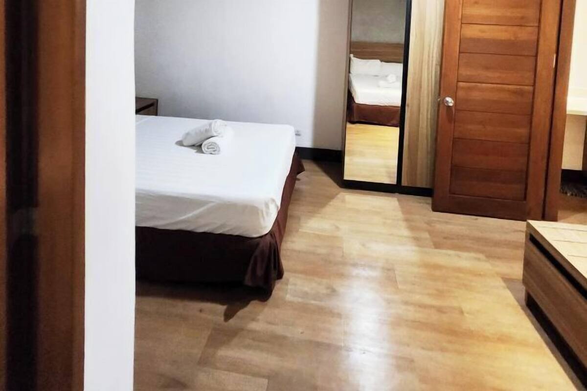 Una habitación de hotel con cama, puerta de madera y espejo.