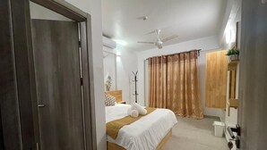 A bedroom with a bed, a ceiling fan, a bedside table, a nightstand, a floor lamp, and a window with curtains. - Spacious 3-bedroom apartment with WiFi, AC in charming Phase 02 (Malé)