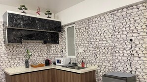 A modern kitchen with a stone wall backsplash, wooden cabinets, a marble countertop, and a built-in microwave. - Spacious 3-bedroom apartment with WiFi, AC in charming Phase 02 (Malé)