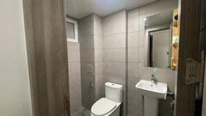 A small, modern bathroom with a toilet, sink, and mirror. - Spacious 3-bedroom apartment with WiFi, AC in charming Phase 02 (Malé)