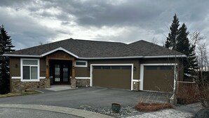 Une maison à deux étages, avec des fondations en pierre, un porche à l’avant et un garage.