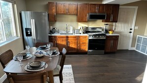 Une cuisine dotée de meubles en bois, d’un réfrigérateur en acier inoxydable, d’une cuisinière et d’une table à manger, cette dernière étant mise avec des assiettes et des verres.