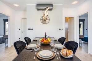 A modern dining room with a long table, black chairs, and a fruit bowl centerpiece. - Villa Gigi With Private Pool (Visnjan)