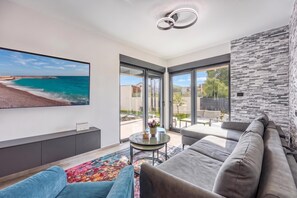 A modern living room with a large TV, comfortable seating, and a view of the sea. - Villa Gigi With Private Pool (Visnjan)